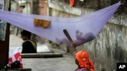 FILE - A woman laborer pacifies her child while cleaning a manhole on a sidewalk in Mumbai, India. Approved in September 2015, the sweeping 15-year agenda approved by the 193 U.N. member states is a global "to-do" list to tackle such issues as climate change, education, hunger, joblessness and land degradation.
